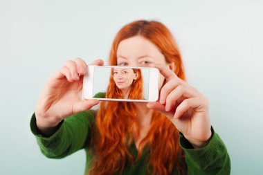 Kızıl saçlı kız telefonu kullanarak selfie yapma. Pozitif, yaşam tarzı, teknoloji ve sosyal ağ