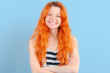 Kızıl saçlı kız gülümsüyor, meme mavi zemin üzerine ellerinde kombine. Pozitif ve onay