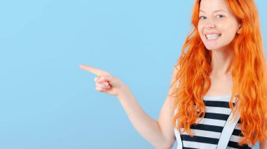 Kızıl saçlı kız gülümsüyor ve onun işaret parmağı ile puan. Promosyon ve ürünler gösterimi için şablon
