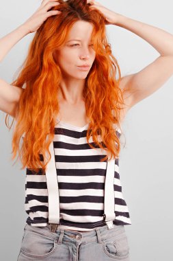 Kızıl saçlı kız saçları ile parmaklarını koştu ve kısarak. Şüphe veya çıkarmama kararı. Duygu ve yaşam tarzı