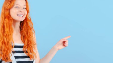 Kızıl saçlı kız gülümsüyor ve onun işaret parmağı ile puan. Promosyon ve ürünler gösterimi için şablon