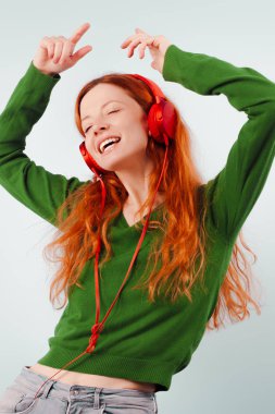 Kızıl saçlı kız kulaklıklar müzik ve dans. Pozitif, yaşam tarzı ve teknoloji