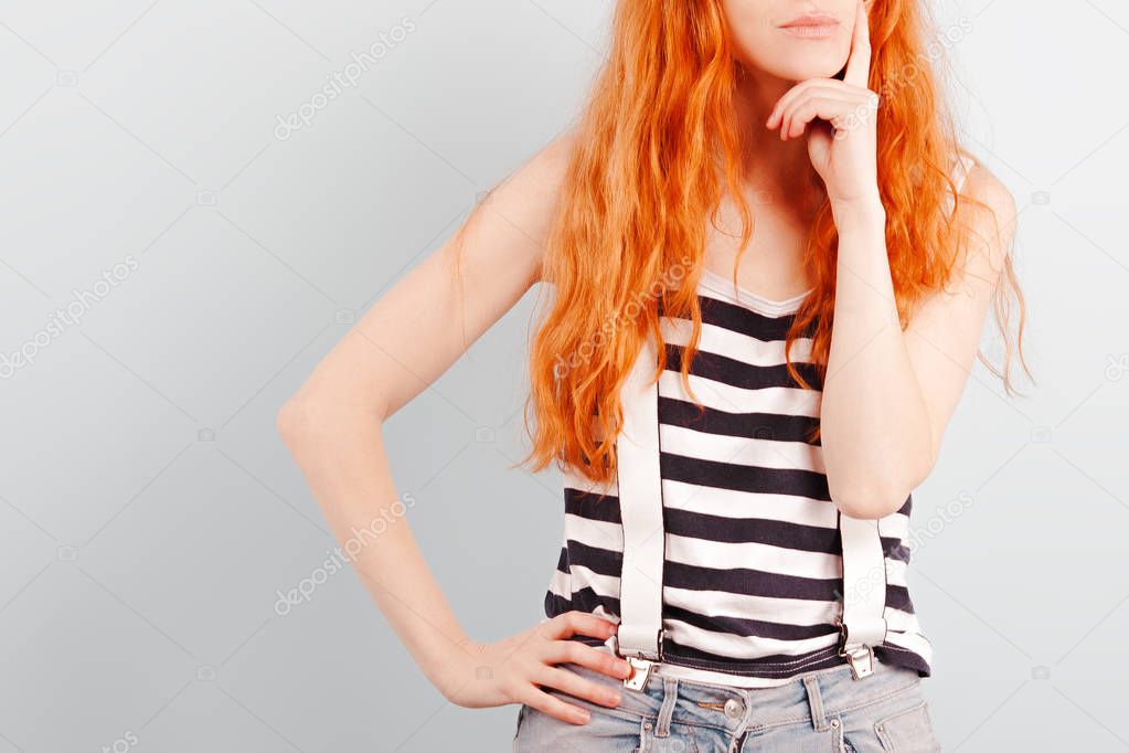 Redhead girl squints and frowns. Doubt, choice and suspicion. Emotions and lifestyle