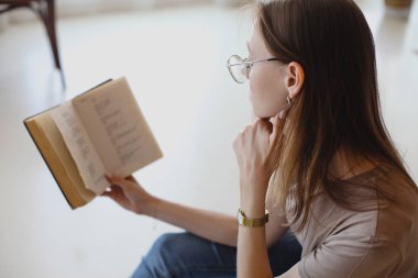Gözlüklü genç tatlı kız oturur ve kitap okur