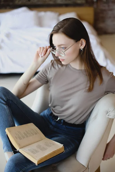 Jeune fille douce avec des lunettes s'assoit et lit livre — Photo