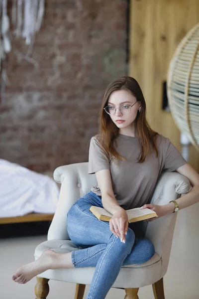 Jeune fille douce dans des lunettes pensée avec le livre dans ses mains . — Photo