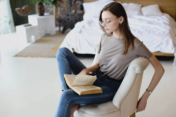 Jeune fille douce avec des lunettes s'assoit et lit livre — Photo