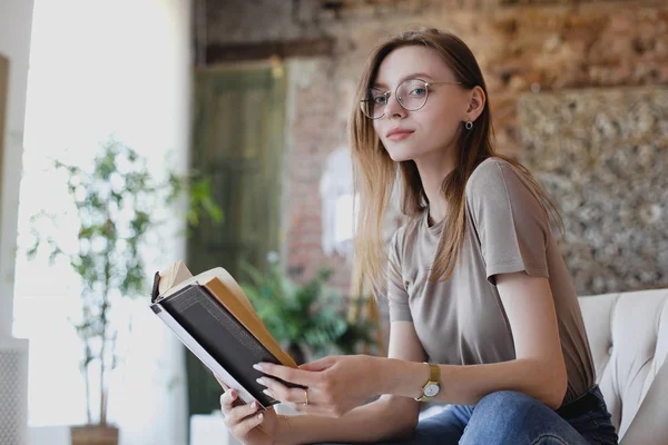 Jeune fille douce avec des lunettes s'assoit et lit livre — Photo