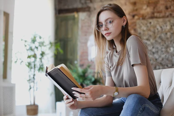 Jeune fille douce avec des lunettes s'assoit et lit livre — Photo