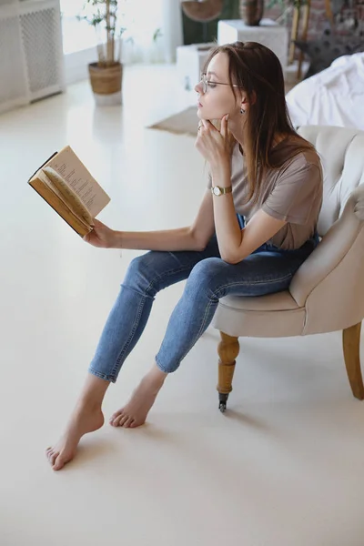 Jeune fille douce avec des lunettes s'assoit et lit livre — Photo