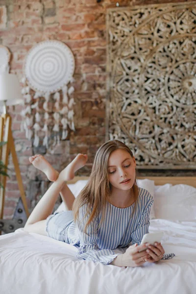 Jong lief meisje liggend op bed met telefoon — Stockfoto