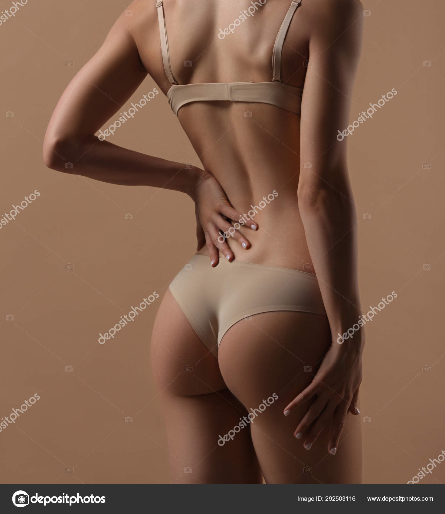 Thin young woman in underwear on beige background Stock Photo by