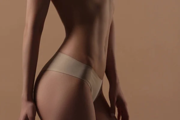 Tunn ung kvinna i underkläder på beige bakgrund — Stockfoto