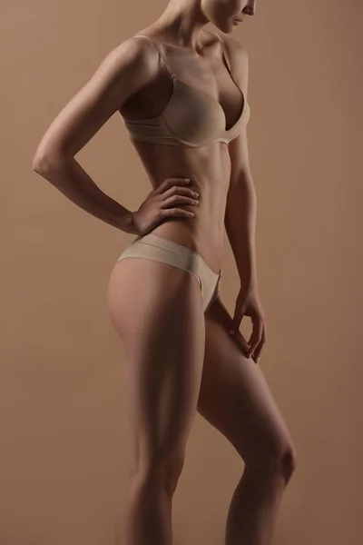 Dunne jonge vrouw in ondergoed op beige achtergrond — Stockfoto