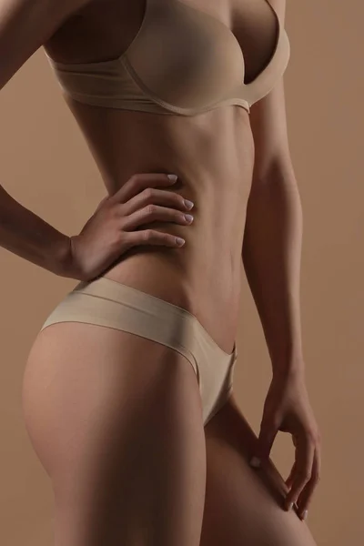 Tunn ung kvinna i underkläder på beige bakgrund — Stockfoto