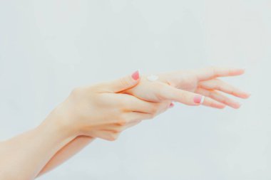 Fransız manikürlü bir kadın ellerine krem sürüyor. El bakımı ve masaj. Eller yukarı.