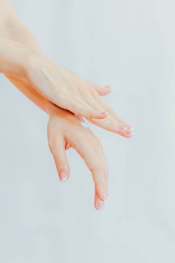 Fransız manikürlü bir kadın ellerine krem sürüyor. El bakımı ve masaj. Eller yukarı.