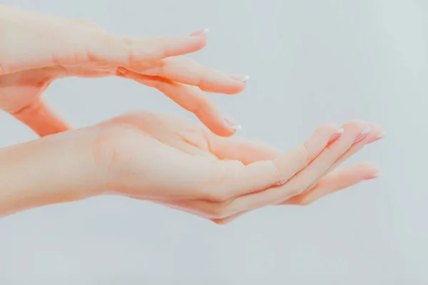 Woman with french manicure applies cream to her hands. Hand skin care and massage. Hands close up