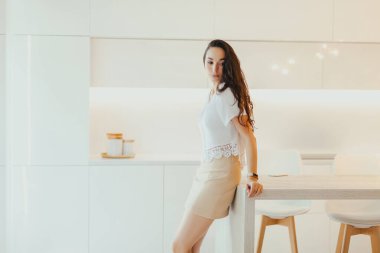 Üzgün genç kadın minimalist tasarımı ile hafif mutfakta duruyor. Duygular ve ruh hali