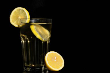 A yakın çekim, limonlu çay limon ve üzerinde siyah bir arka plan ile glas ile glas