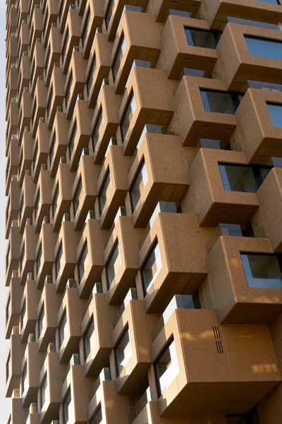 Close up of a building that is made up of several square boxes with windows. Hard light from the left with strong shadows