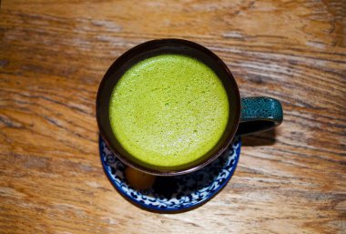 En iyi manzara sıcak yeşil çay, siyah bardakta, ahşap masada.