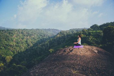 Asyalı kadınlar tatilde rahatlar. Yoga varsa oynayın. Moutain kayalıklarında. Tayland dağ ormanlarının doğası