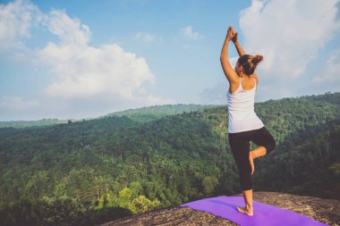 Asyalı kadınlar tatilde rahatlar. Yoga varsa oynayın. Moutain kayalıklarında. Tayland dağ ormanlarının doğası