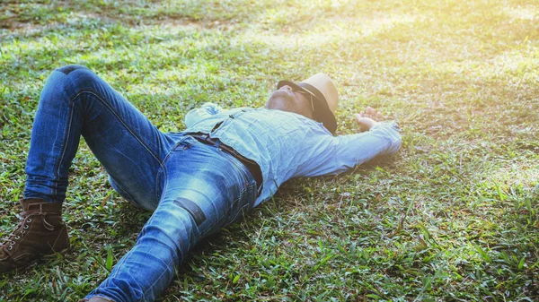 Asijský muž se v prázdni cestuje. Spánek Relaxujte na trávníku — Stock fotografie