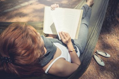 Kadınlar uyurken kitap okuyor. Hamakta. Parktaki doğal atmosferde