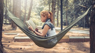 Women sitting reading. In the hammock. In the natural atmosphere in the park clipart