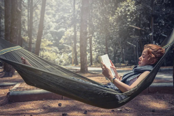 Kadınlar uyurken kitap okuyor. Hamakta. Parktaki doğal atmosferde