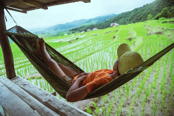 Asian woman travel nature. Relax read a book in the hammock. the balcony of the resort. View of the field on the Mountain in summer. Thailand