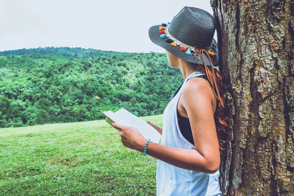 Las mujeres asiáticas se relajan en las vacaciones. Stand leer libros sobre pastizales en el parque. educación, leer un libro, libro, Escribir una nota, diario, naturaleza, al aire libre, vacaciones, deporte, ejercicio, relajarse, viajar Tailandia, verano . — Foto de Stock