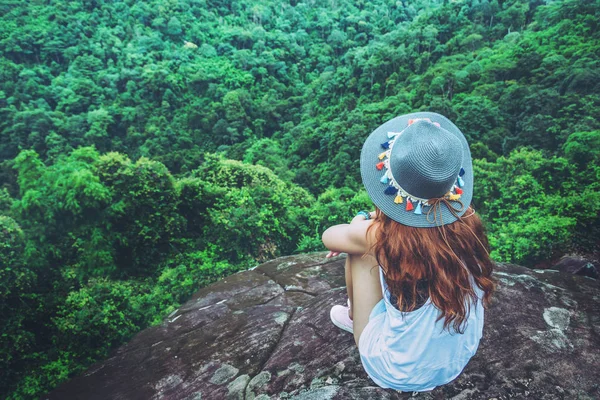 As mulheres asiáticas viajam relaxar nas férias. sentar-se em um penhasco rochoso . — Fotografia de Stock