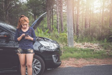 Kadınlar bozuk arabayla iletişim kurmak için telefonu kullanır..