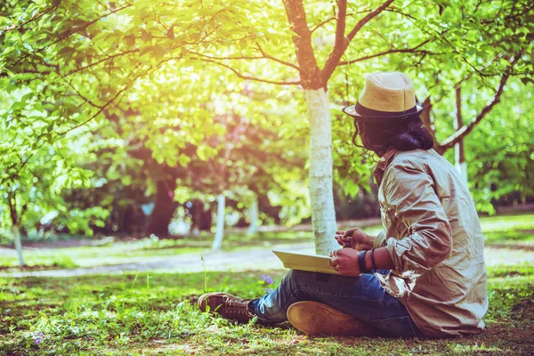 Hombre asiático viajar naturaleza. Relájate. dormir libro de lectura En el césped en el parque. en verano . — Foto de Stock