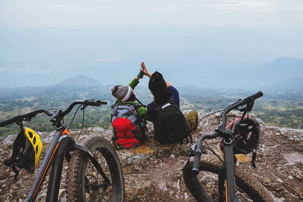 Asiatico amante donna e uomo Viaggi Natura. Viaggio relax andare in bicicletta Wilderness in natura. Sedetevi su una scogliera rocciosa . — Foto Stock