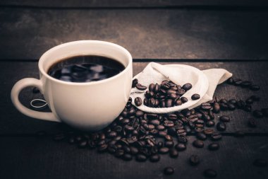 Sıcak kahve beyaz bir fincan da kahve çekirdekleri ile ahşap zemin koyun