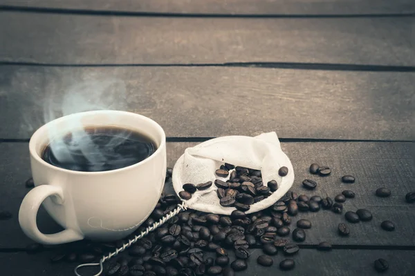 Café chaud est dans une tasse blanche Mettez sur le sol en bois avec des grains de café — Photo