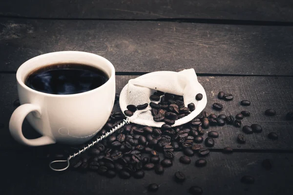 Café chaud est dans une tasse blanche Mettez sur le sol en bois avec des grains de café — Photo