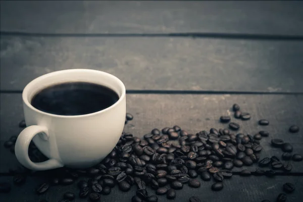 Café caliente en una taza blanca Poner en el suelo de madera con granos de café — Foto de Stock