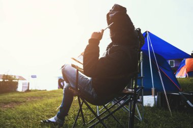 Asyalı adam tatilde rahatlayın seyahat. genç adam dağda doğa kamp seyahat. sandalyeye bir not yazmak oturuyor bir kitap okuyun. kamp çadırı, kamp Tayland, eğitim, kitap, not yaz, günlük.