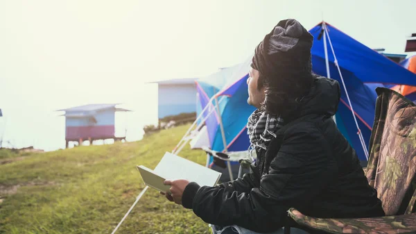 Aziatische man reizen ontspannen in de vakantie. Man reizen natuur kamperen op de berg. zittend Natural Touch mist. camping tent, Camping Thailand, onderwijs, boek lezen, boek, schrijf een notitie, dagboek. — Stockfoto