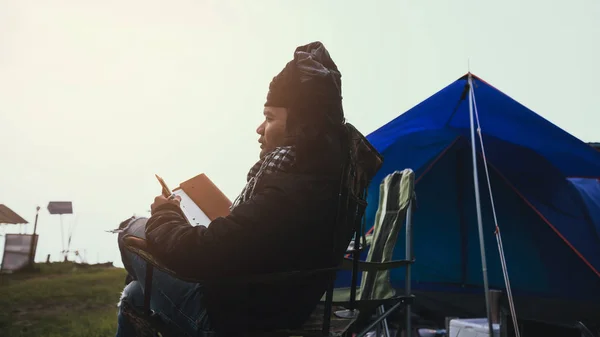 Asian man travel relax in the holiday. Man travel nature camping on the Mountain. sitting natural touch fog. camping tent, camping Thailand, education, read a book, book, Write a note, diary.