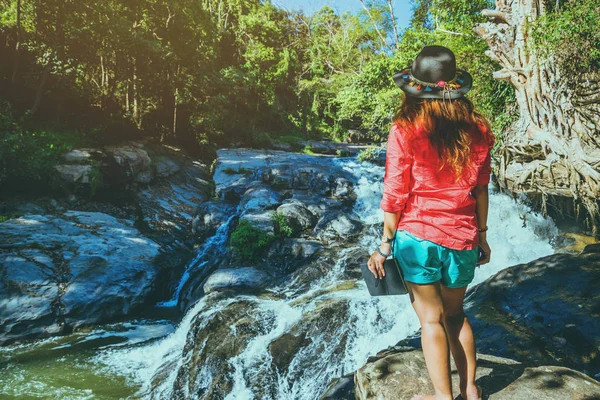 Asian woman travel nature. Travel relax. Study read a book. Nature Education Write a note At Waterfall Use summer. education, read a book, book, Write a note, diary, nature, outdoor, holiday, relax, travel, summer, waterfall, travel Thailand.