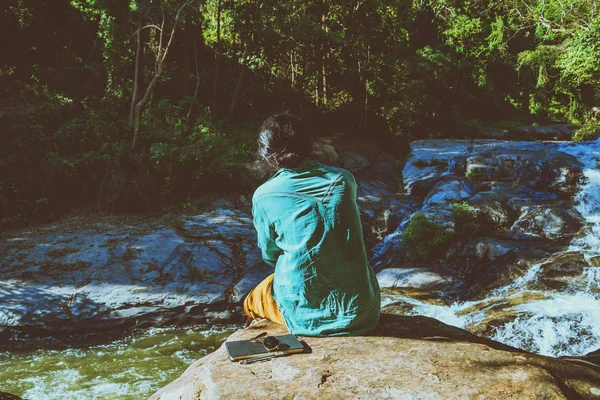 Asian człowiek podróżować natura. Podróże relaks. Studiować czytać książkę. Edukacja przyrodnicze napisz notatkę na wodospad Użyj lato. W Tajlandii — Zdjęcie stockowe