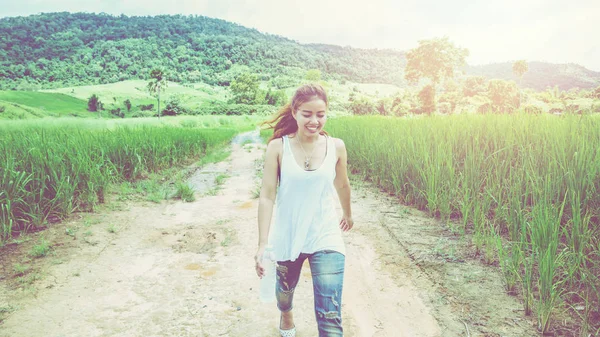 Asian women travel relax in the holiday. Walk on the middle of the meadow road. rice field, countryside, forest, nature, outdoor, holiday, relax, travel, summer, travel Thailand.