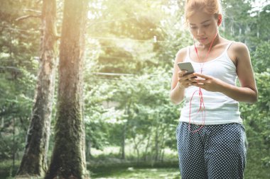 Kadınlar müzik dinlerler. Doğa parkında dinlenirler. Seyahat, rahatlama, Tayland seyahati. communication, Technology, phone, listen music.