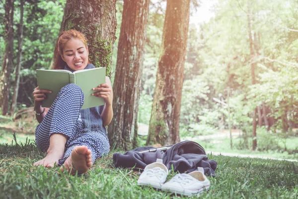 Leer mujeres relajarse en el parque, bosque de pinos, bosque de vacaciones. Las mujeres jóvenes disfrutan y disfrutan leyendo. lectura, educación, libro, encontrar conocimiento . — Foto de Stock